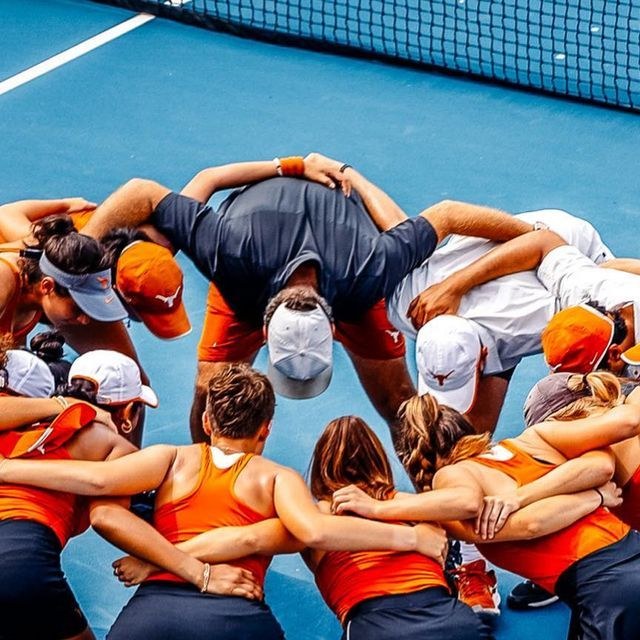 A college tennis team in a huddle with their coach on court