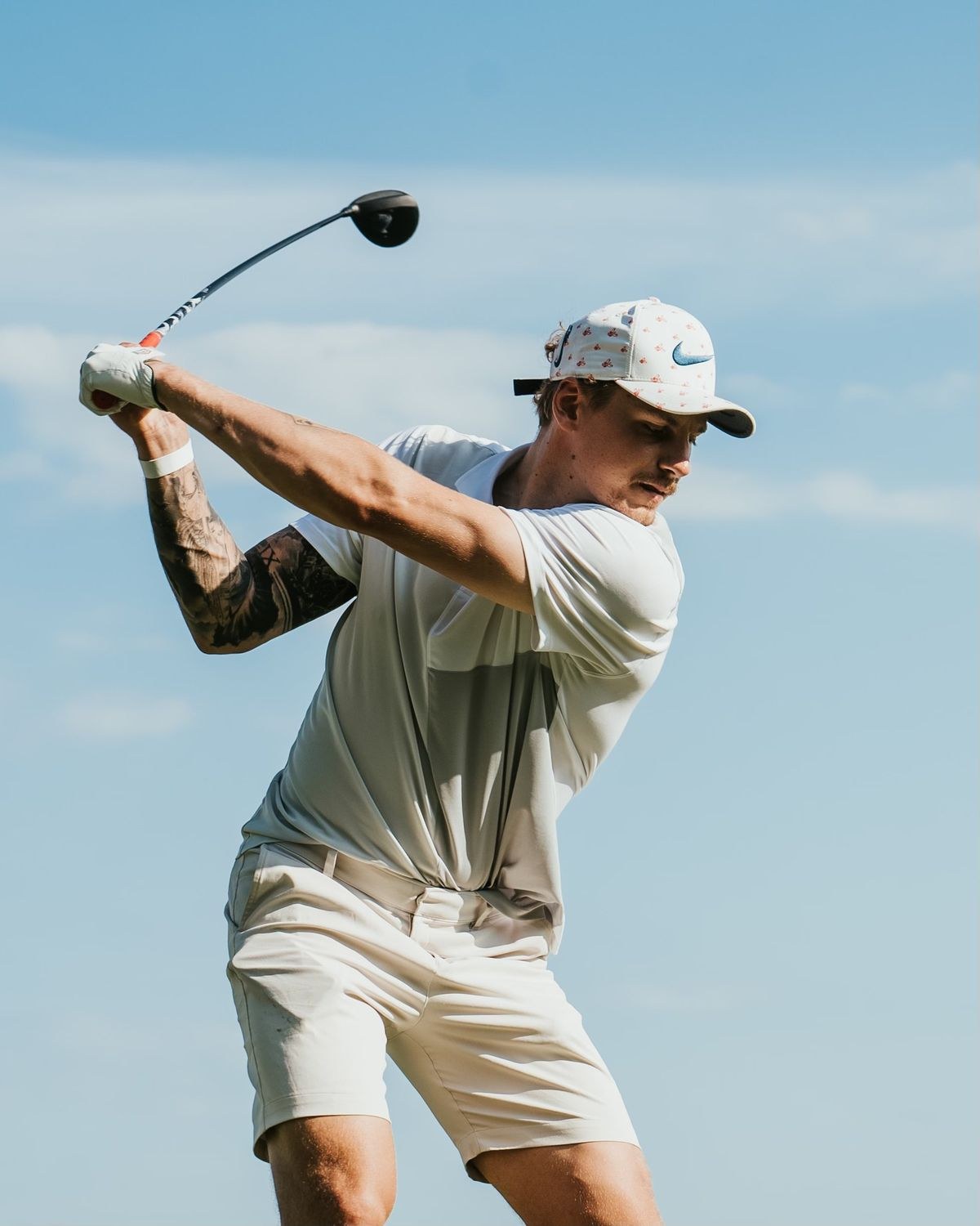 Golfer at the top of his backswing against a blue sky