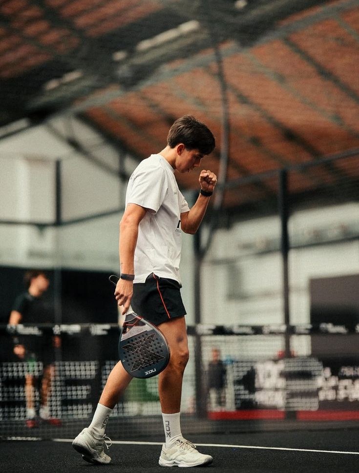 Padel coach walking on an indoor court with his racket