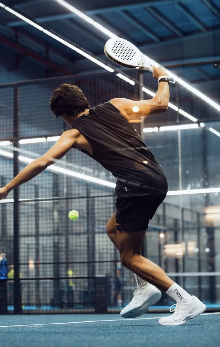 Padel player hitting an overhead on an indoor court