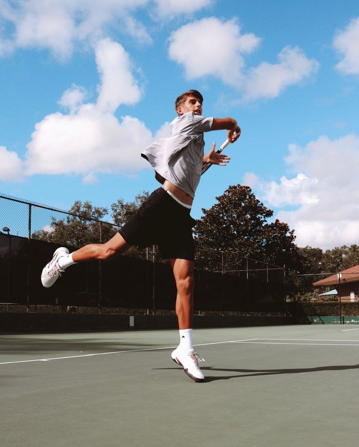 Tennis player jumping into a serve on an outdoor hard court