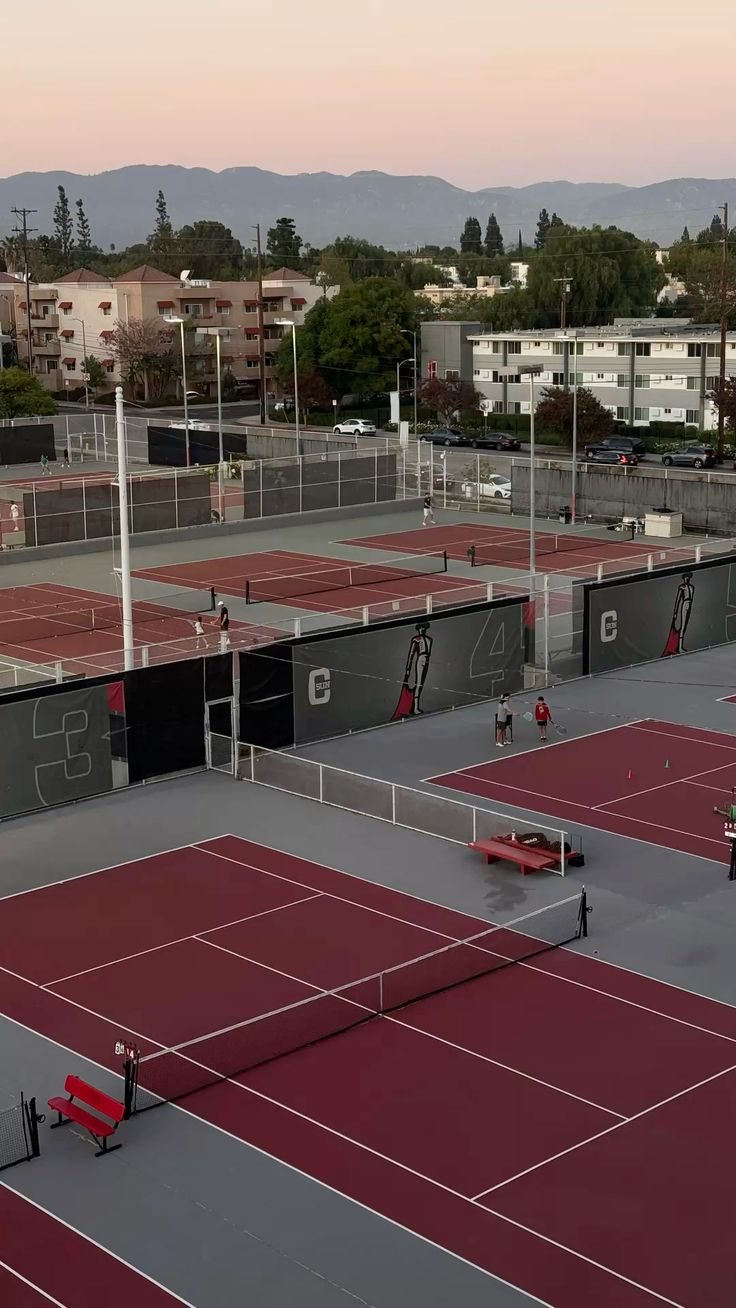 College tennis courts on a U.S. campus at dusk, with the mountains behind