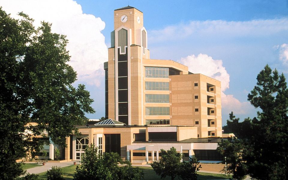 The Dean B. Ellis Library and its clock tower, framed by trees under a blue sky, on Arkansas State University&rsquo;s campus in Jonesboro, Arkansas (archival photo)