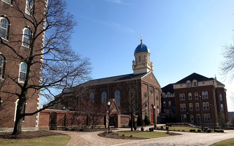 The Chapel of the Immaculate Conception, with its blue dome and cream cupola, among red-brick buildings on the University of Dayton campus in Dayton, Ohio, under a clear late-winter sky