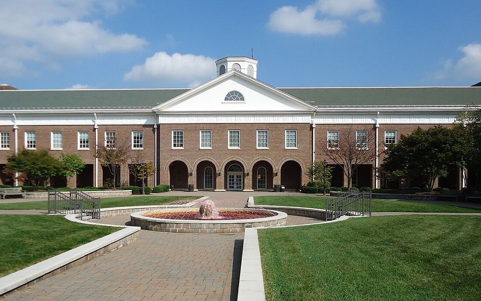 A red-brick building with a white cupola and arched arcade behind a fountain courtyard on The College of New Jersey campus in Ewing, New Jersey